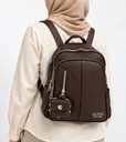 شنطة ظهر حريمي من الجلد الصناعي باللون البني أثناء ارتدائها، مع الجيوب الأمامية والمحفظة الصغيرة المعلّقة