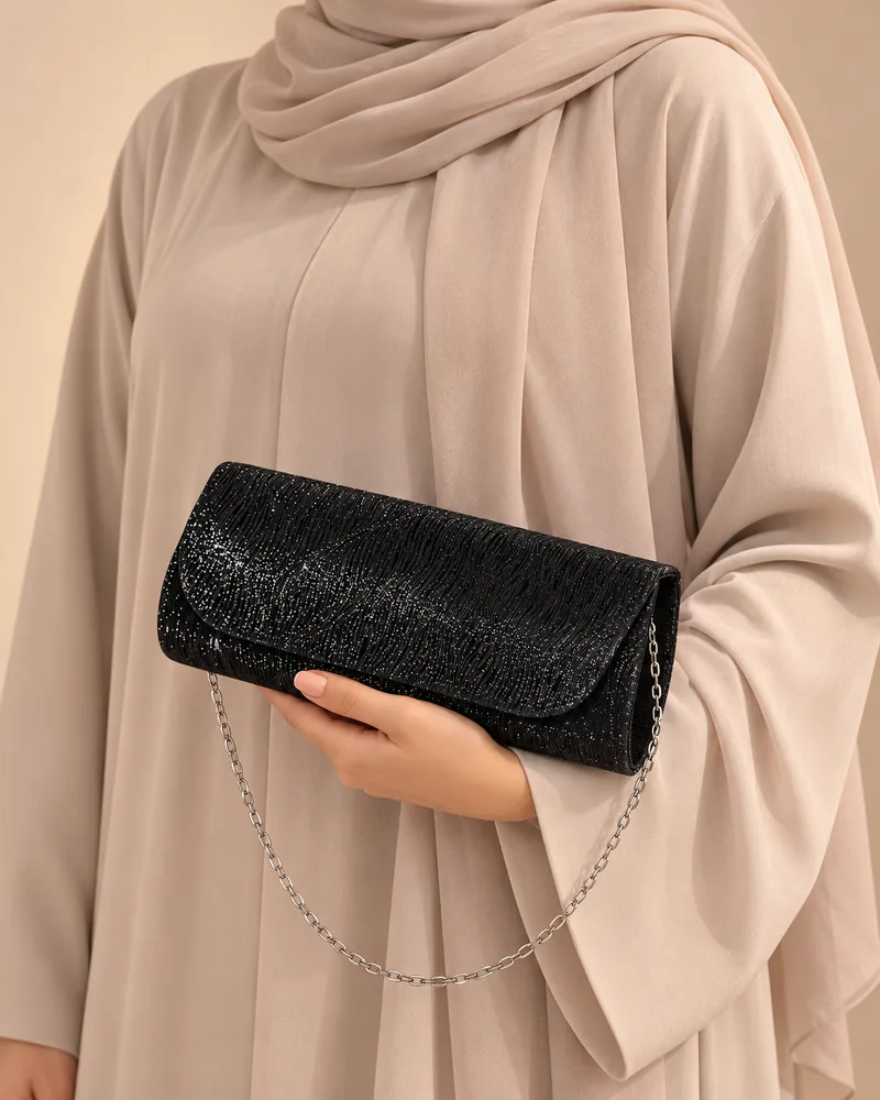 كلاتش سهرة طويلة ميتاليك باللون الأسود مع موديل محجبة تمسكها باليد