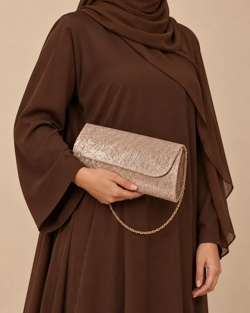 كلاتش سهرة طويلة ميتاليك باللون الذهبي مع موديل محجبة تمسكها باليد
