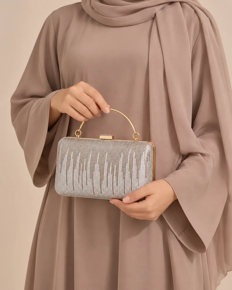 كلاتش سهرة علبة بالستراس باللون الفضي مع موديل محجبة تمسكها باليد