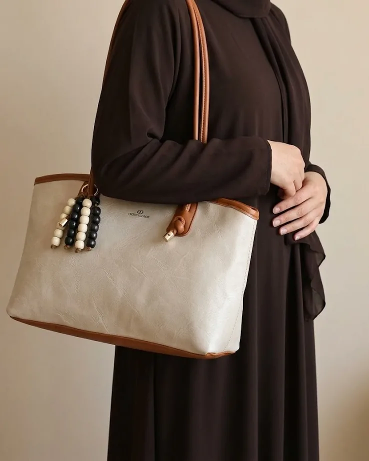 شنطة كتف حريمي بلونين بحواف ملونة ودلاية خرز باللون البيج الفاتح مع موديل